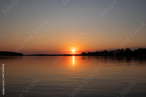 Red sunset on the river. Evening. The rays of the sun in the clouds