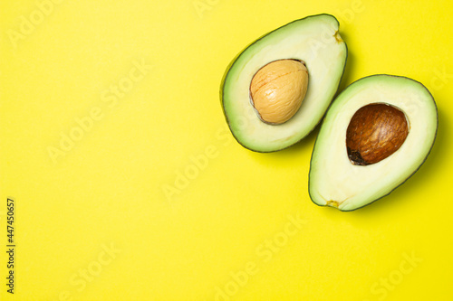 Avocado on a yellow background. Cut avocado on colored background