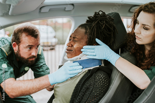 Paramedic placing a cervical collar to an injured woman from car accident photo