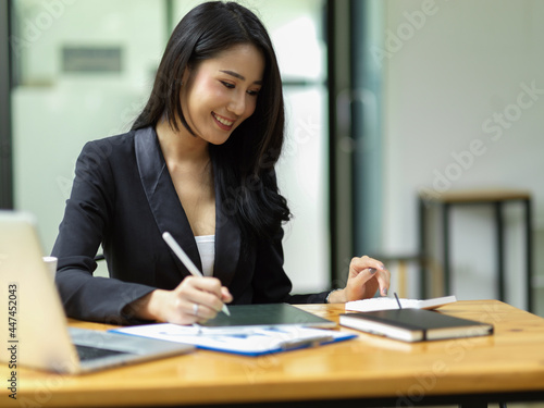 Young asian CEO female calculating project budget via smart digital tablet