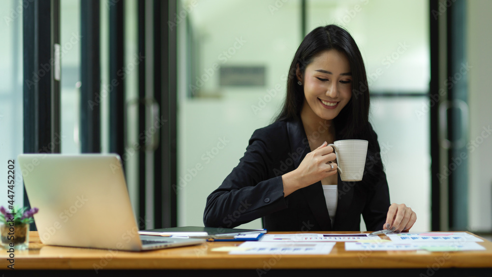 Adult businesswoman sitting and drinking coffee during working at office Adult businesswoman sitting and drinking coffee during working at office