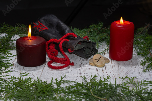 Gebo rune, a bag of runes, and a background of candles with selective focus.The meaning of the rune that fell out during divination: to unite, without encroaching on each other's freedom, mutual love. photo