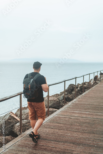 man with backpack walking by sea quay