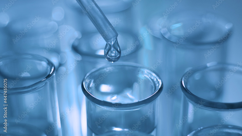 Dropping chemical liquid to test tubes for lab testing, science laboratory research and development concept, blue tone Dropping chemical liquid to test tubes for lab testing, science laboratory research and development concept, blue tone