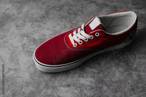 New pair of red sneakers isolated on dark background with copy space. Sport shoes lifestyle.