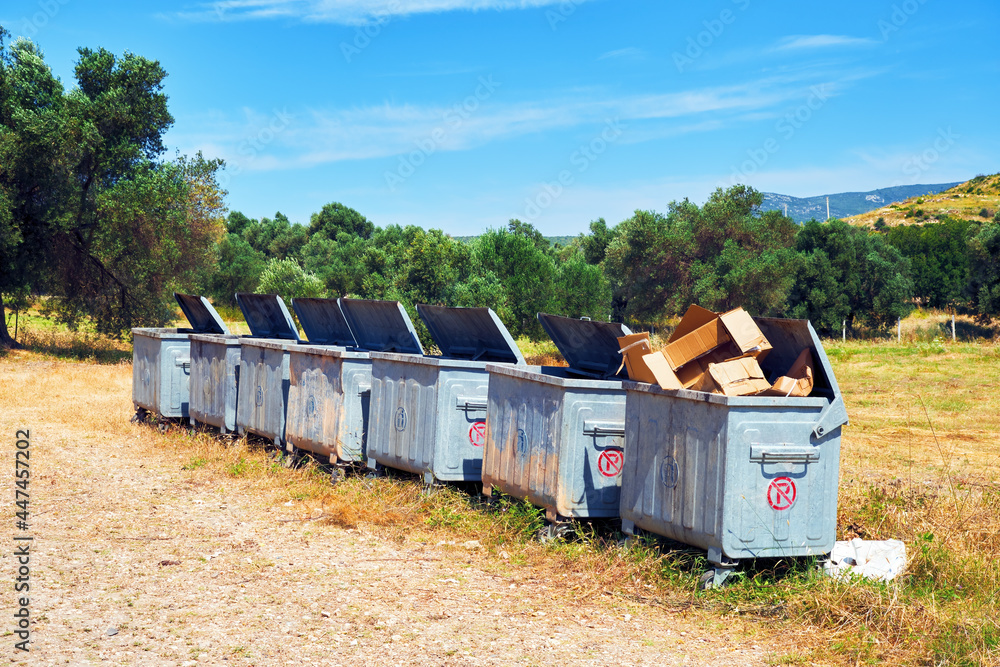 Metal garbage containers in a row in a rural field Metal garbage containers in a row in a rural field