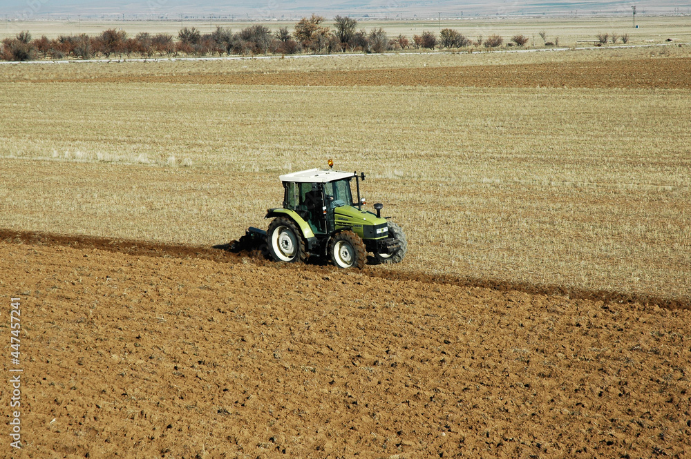 Obraz premium photo of green tractor plowing the field