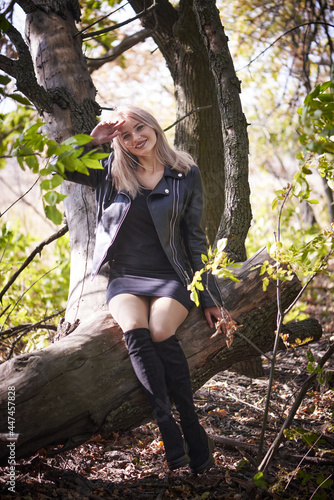 Sexy young woman in a little black dress and biker jacket relaxing in nature