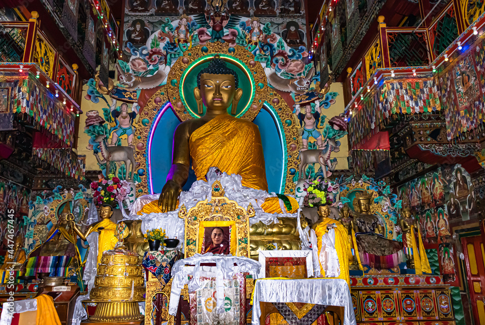 huge buddha golden statue decorated with religious flags and offerings at evening