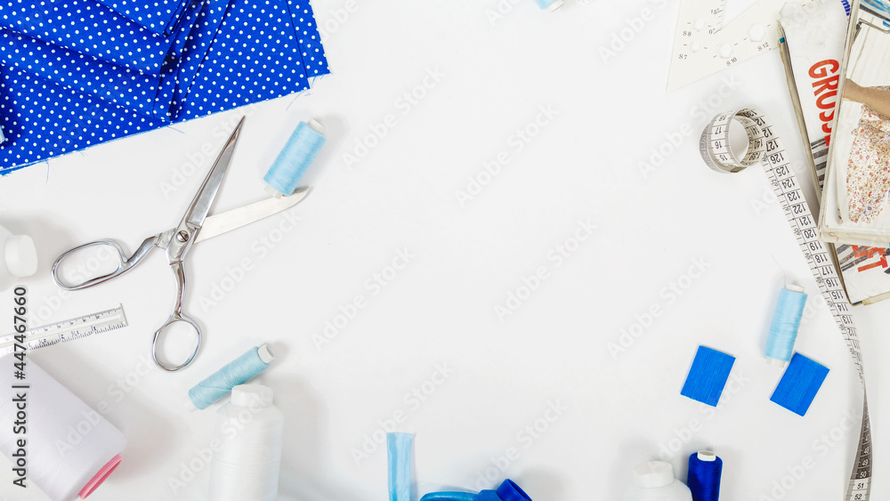 sewing business. Tailor's workplace with threads, scissors, template, spools, blue fabric. white background top view space for text in the frame. Tailoring concept