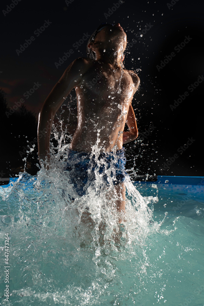 Portrait of active boy in the pool at night