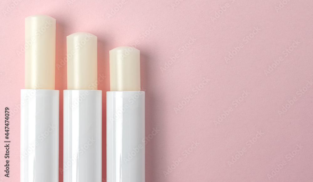 View from above of three lip balm tubes on pink background. View from above of three lip balm tubes on pink background.