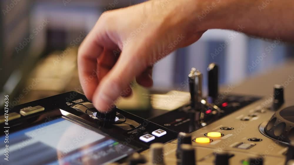 The DJ at the disco is working behind the remote control. Close-up of the DJ's hands on the control panel The DJ at the disco is working behind the remote control. Close-up of the DJ's hands on the control panel