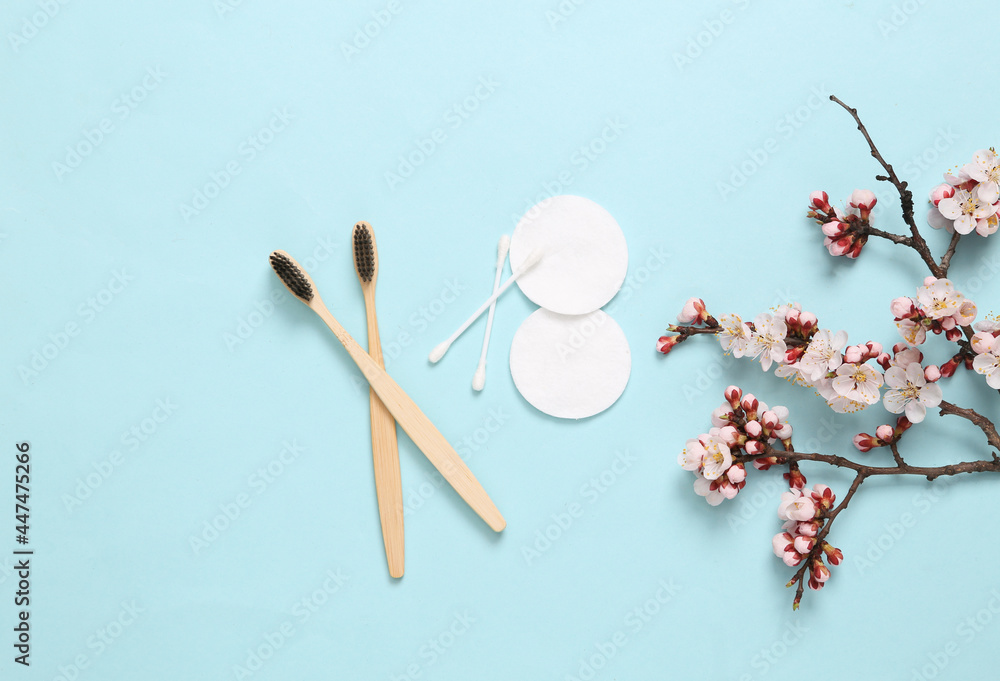 Toothbrushes, hygienic cotton pads and ear sticks on blue background with flowering branches. Hygiene concept Toothbrushes, hygienic cotton pads and ear sticks on blue background with flowering branches. Hygiene concept