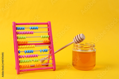 Abacus with Bee honey jar and honey wooden spoon on yellow background