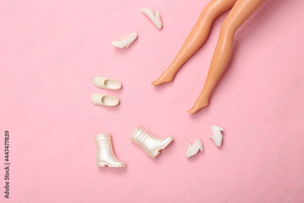 Doll feet chooses shoes on pink background. Minimalistic fashion layout