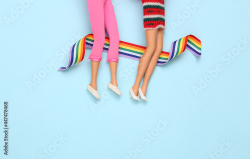 Fotografia, Obraz Doll female legs with lgbt rainbow tape on blue background