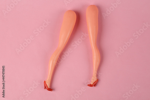 Torn off doll legs on a pink background. Minimalism. Concept art photo
