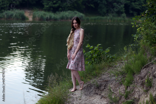 Long haired woman in pink dress standing near water © Сергей Луговский