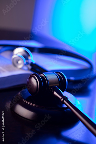 Medical law concept. Gavel  legal code and stethoscope on the glass table. Blue light.