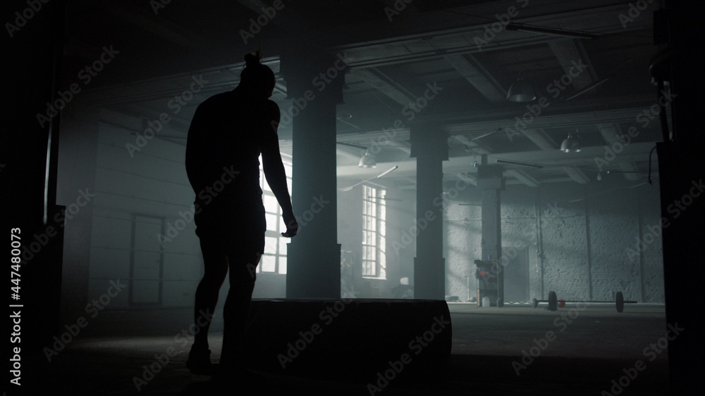 Fototapeta premium Powerful man lifting rubber tire. Male athlete working with heavy weights