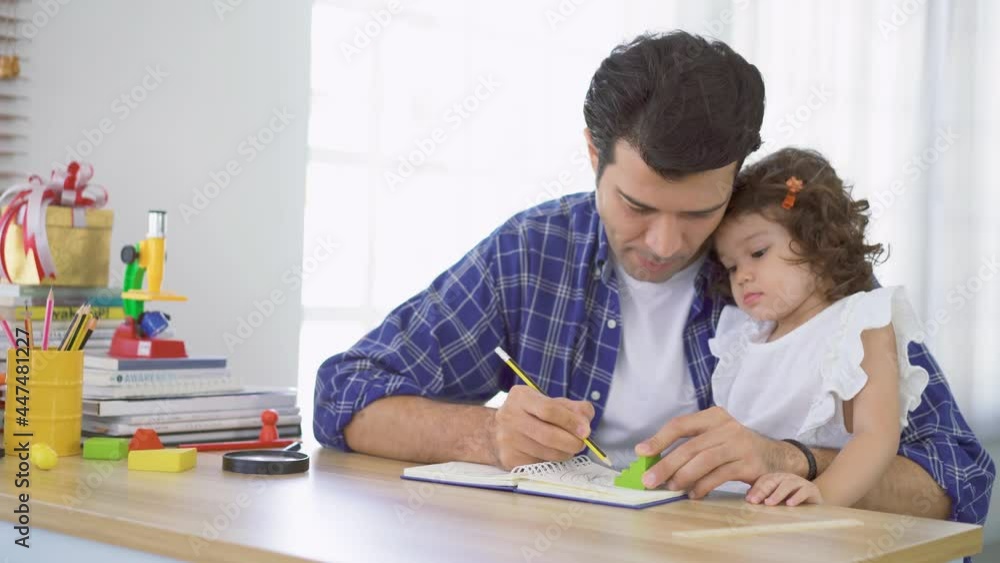 Portrait of young father teaching his cute little daughters' study. Excited smiling small child girl enjoying learning with pleasant dad at home. Children education, home schooling concept Portrait of young father teaching his cute little daughters' study. Excited smiling small child girl enjoying learning with pleasant dad at home. Children education, home schooling concept
