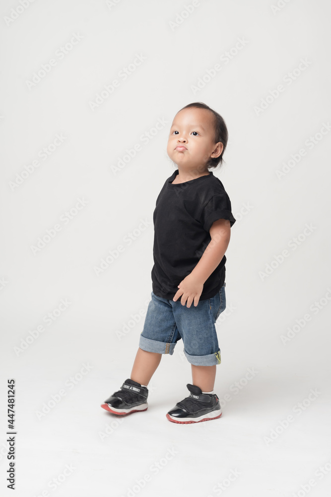 Asian boy wearing denim overalls is walking.