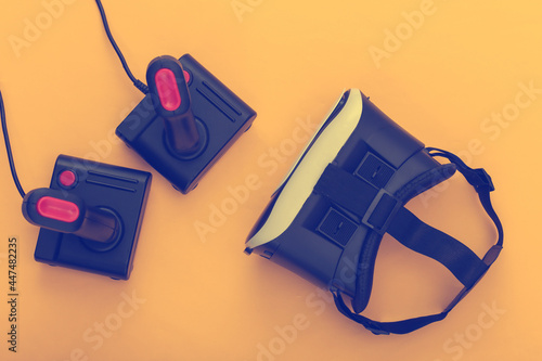 Virtual reality headset and retro joysticks on a yellow background. Entertainment, video game. Top view