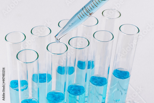 Laboratory test tubes with blue reagent and pipette with drop. Medical research concept.