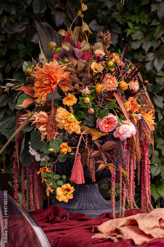 Autumn floral bouquet in pumpkin vase. Decoration of flowers in woman hands