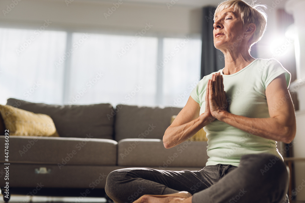 Senior woman sitting in Lotus position and meditating at home Senior woman sitting in Lotus position and meditating at home