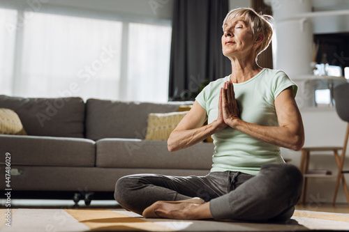 Foto Senior woman sitting in Lotus position and meditating at home