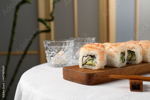 Delicious sushi rolls with shrimps served on white table indoors, space for text