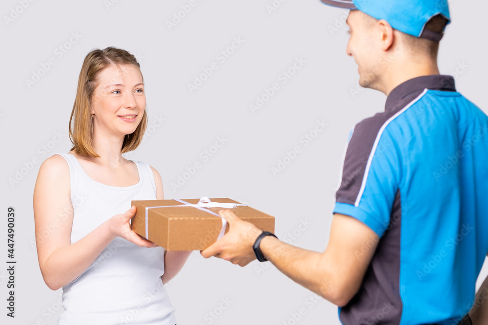 Satisfied blonde woman in white t-shirt takes the delivery carton box from the courier man in uniform. Satisfied blonde woman in white t-shirt takes the delivery carton box from the courier man in uniform.
