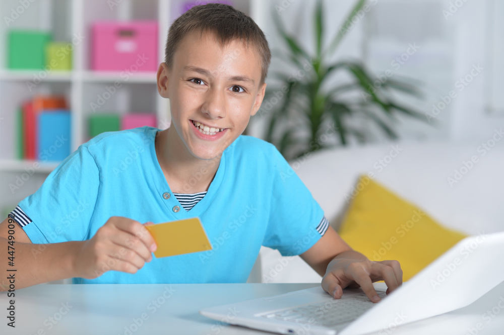 Boy using modern laptop at home shopping online Boy using modern laptop at home shopping online