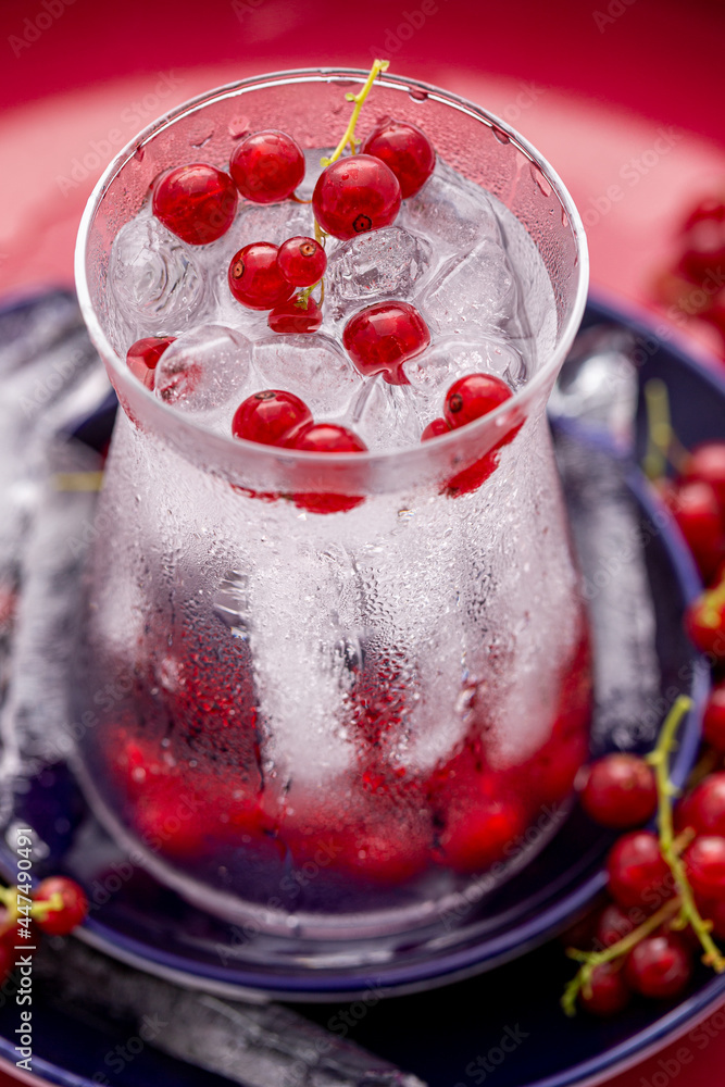 custom made wallpaper toronto digitalErfrischendes Wasser mit Eiswürfel und Johannisbeeren im formschönen Glas auf blauen Tellern vor rotem Hintergrund