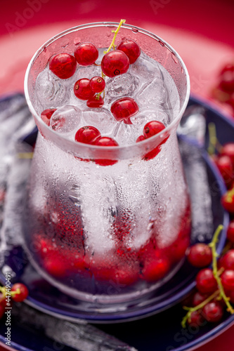 Wallpaper Mural Erfrischendes Wasser mit Eiswürfel und Johannisbeeren im formschönen Glas auf blauen Tellern vor rotem Hintergrund Torontodigital.ca