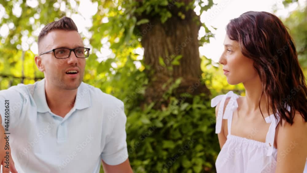 leisure and people concept - happy couple talking at summer park leisure and people concept - happy couple talking at summer park
