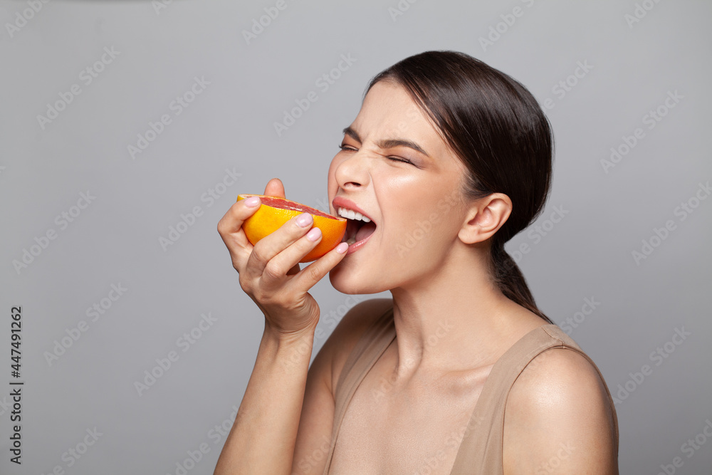 Beautiful enthusiastic woman biting grapefruit on white Beautiful enthusiastic woman biting grapefruit on white