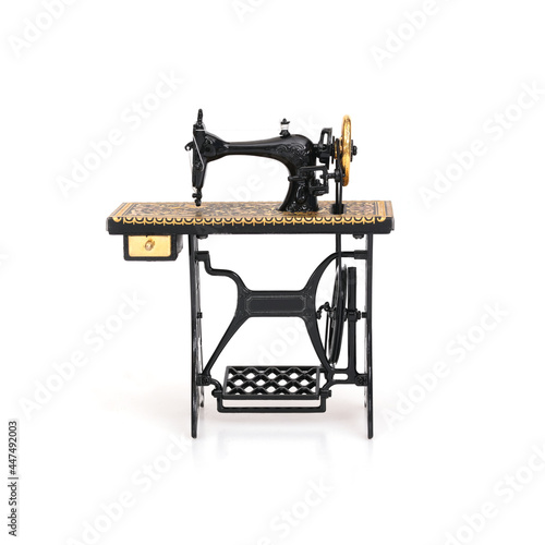 Miniature model of sewing machine with gold ornament isolated on white background