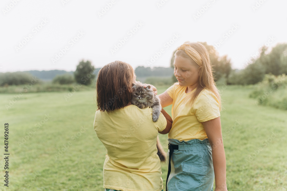Children portrait with kitten in park. Girls playing outdoors with cat Children portrait with kitten in park. Girls playing outdoors with cat