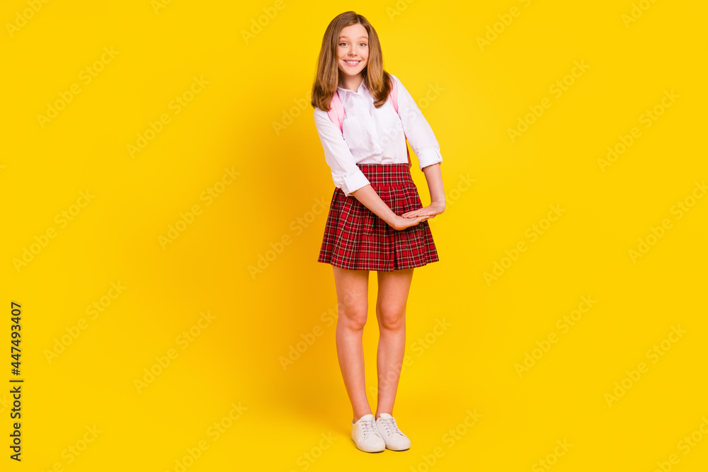 Full length photo of cute small girl hold hands wear shirt skirt bag sneakers isolated on yellow background