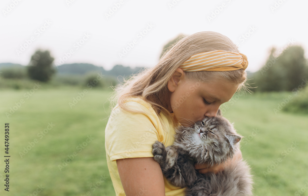 Portrait with kitten in park. Girl play outdoors with cat