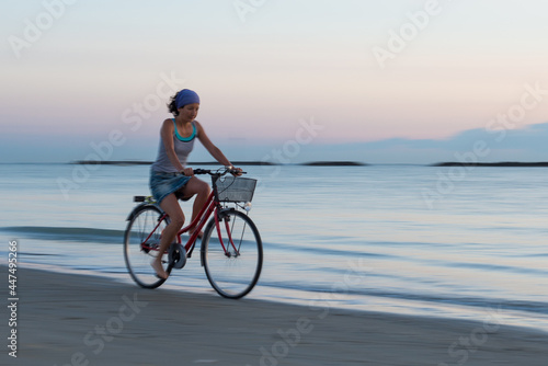 Young woman during a bicycle trip at the beach early in the morning