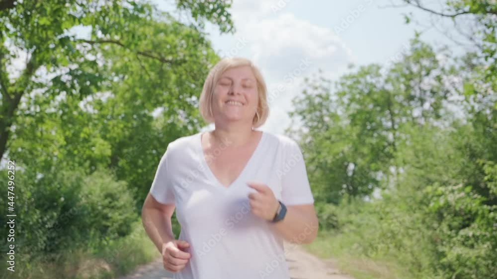 Close up video of the happy woman running along the forest path looking at the video camera with smiling face. Close up video of the happy woman running along the forest path looking at the video camera with smiling face.
