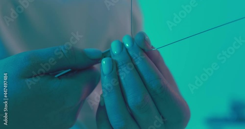 Close-up orthodontist hands are holding an archwire and by using dental forceps are clenching and bending archwire. photo
