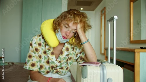 a woman in a hotel room wearing a protective mask and with a suitcase, immediately after the airport to the hotel for quarantine. vacation problem due to coronavirus test