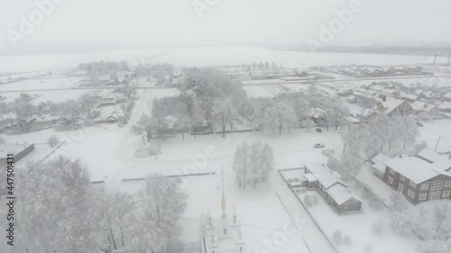 Church of the Kazan icon of Mother of God  in winter during heavy snow in the village of Konstantinovo, Ryazan. Wooden houses and Church in Russia. Aerial view
