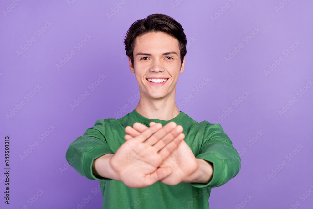 Photo of young guy happy positive smile gesture hand deny reject avoid signal isolated over violet color background Photo of young guy happy positive smile gesture hand deny reject avoid signal isolated over violet color background