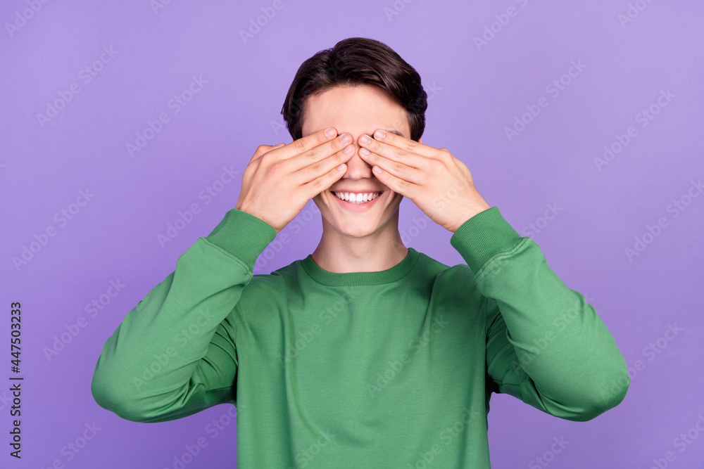 Photo of young guy happy positive smile close cover eyes hands hide peek isolated over violet color background Photo of young guy happy positive smile close cover eyes hands hide peek isolated over violet color background